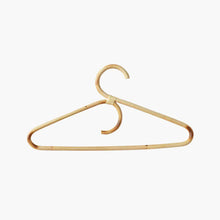 Charger l'image dans la galerie, Lot de cintres pour adultes en rotin naturel suspendus sur une tringle dans une penderie lumineuse et épurée.