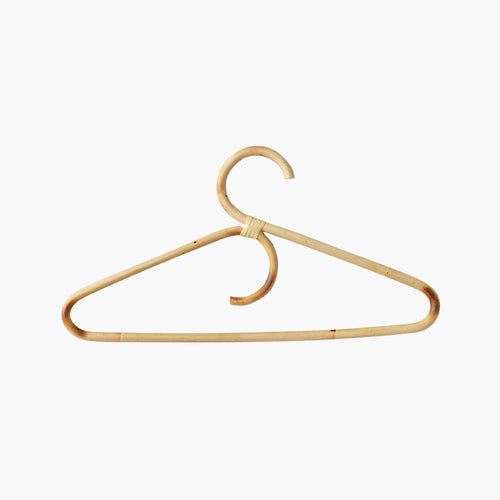 Lot de cintres pour adultes en rotin naturel suspendus sur une tringle dans une penderie lumineuse et épurée.

